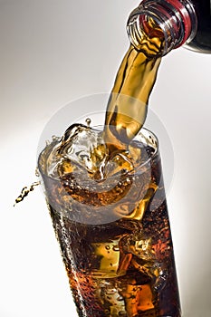 Pouring a glass of Coca-cola with ice cubes