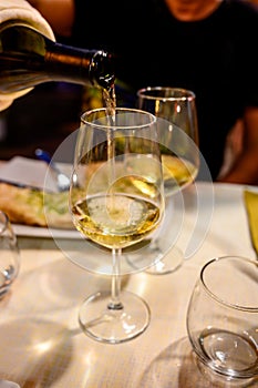 Pouring in glass  cold dry white wine in outdoor cafe at night in Italy