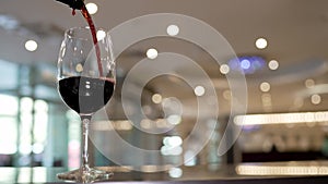 Pouring glass of red wine from a bottle. Waiter pouring red wine. Red wine is poured into a wine glass at the lobby bar