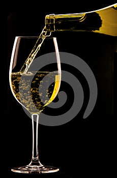 Pouring a glass of wine on black background.