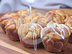 Pouring glaze on cinnamon rolls.