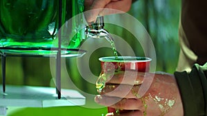 Pouring of green lemonade in a cup in the park