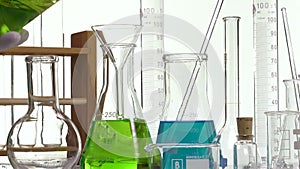 Pouring green liquid in a Erlenmyer flask using a funnel