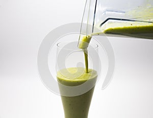 Pouring green smoothie into glass