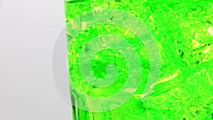 Pouring Green sparkling water with ice cubes close-up