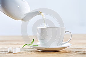 Pouring green tea from white ceramic teapot