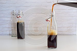 Pouring homemade cold brew coffee from glass jar to glass bottle