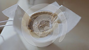 Pouring homemade filter coffee. closeup white cup with paper filter with coffeeground.