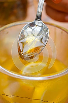 pouring honey in a cup of tea