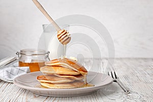 Pouring honey onto tasty pancakes