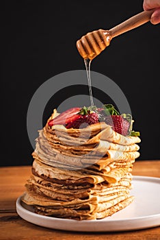 Pouring honey over blini, crepes