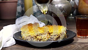 pouring honey sirup on Traditional homemade arabic sweets (dessert kadaif, kunafa, baklava), ramadan kareem concept.