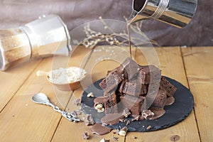 pouring hot chocolate with a metal mug on a stack of bite size brownies