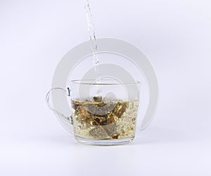Pouring hot water to the glass cup with tea, isolated on white