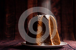 Pouring icing sugar on italian pandoro christmas cake with warm natural light up with warm night giving a feeling of  artisanship