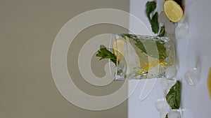 Pouring lemonade into a glass with ice and lemon