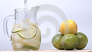 Pouring lemonade into a jug. Homemade lemonade. Drink with fresh lemons and ice.