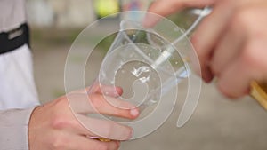 Pouring lemonade into a plastic glass from a glass. Close up shot.