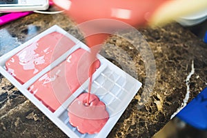 Pouring liquid pink chocolate in a bar mould - Making handmade chocolate bars