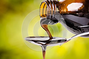 Pouring a liquid on a spoon. Natural green background. Pharmacy and healthy background. Medicine. Cough and cold drug.