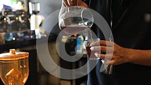 Pouring manually brewed coffee V60 drip in a clear pitcher into a glass. The process of serving brewed coffee