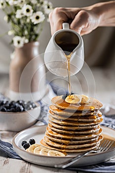 Pouring maple syrup on homemade banana pancakes with blueberry, easy recipes homemade cooking