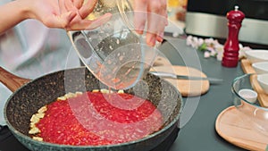 Pouring mashed tomatoes into the pan