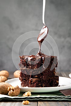 Pouring melted chocolate on brownies with a spoon