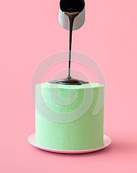 Pouring melted chocolate over peppermint cake, isolated on a pink background