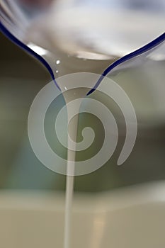 Pouring Milk from a Blueish Measuring Cup photo