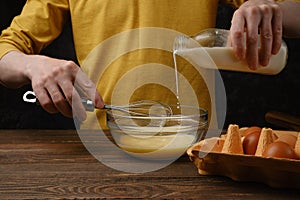 Pouring milk in a bowl with eggs