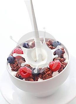 Pouring milk into breakfast cereal with berries