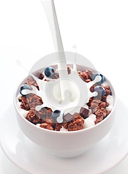 Pouring milk into chocolate cereal with berries