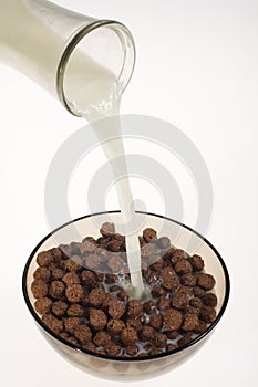 Pouring milk into chocolate cereal bowl