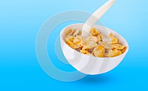 pouring milk into corn flakes creating splash isolated on white background