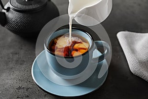 Pouring milk into cup of black tea