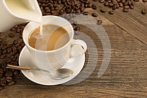 Pouring milk in a cup of coffee.