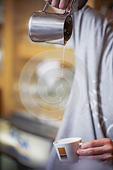 Pouring milk in a espresso coffee cup