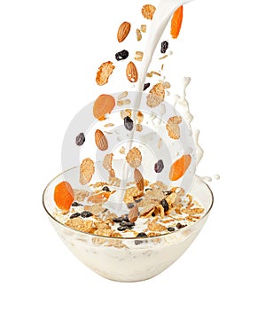 Pouring milk and falling muesli over a transparent bowl. Isolated on white.