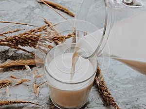 Pouring milk in the glass on blue background. Fresh milk pouring making a crown splash. Front view. Milk glass top view.