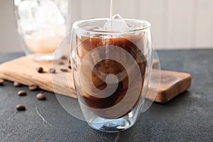 Pouring milk into glass with cold brew coffee