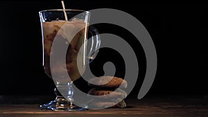 Pouring milk into glass of cold brew coffee on dark background