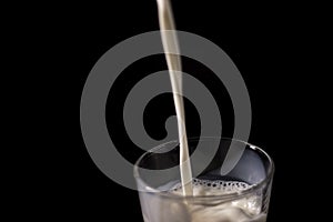 Pouring milk in a glass. splash of white liquid isolated on dark background