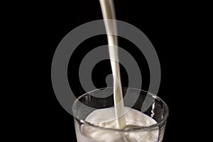 Pouring milk in a glass. splash of white liquid isolated on dark background