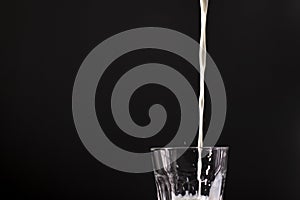 Pouring milk in a glass. splash of white liquid isolated on dark background