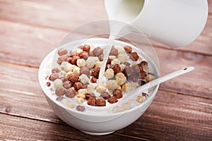 Pouring milk from jar in bowl of corn flakes