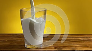 Pouring milk from jug to glass on a rustic wooden table