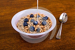 Pouring Milk on Oat Cereal with Blueberries