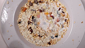 Pouring milk over cereals and dried fruits for breakfast