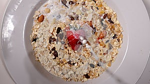 Pouring milk over cereals and dried fruits for breakfast